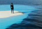 A tranquil image of a person standing alone on a deserted island, looking out at the vast, endless ocean, symbolizing isolation, introspection, and self-discovery.