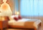 A calming, serene image of a person resting in a cozy bedroom, lying on a bed and looking relaxed, with soft lighting creating a peaceful atmosphere. The room exudes comfort and tranquility, with warm tones and soft textures to evoke a sense of restfulness.